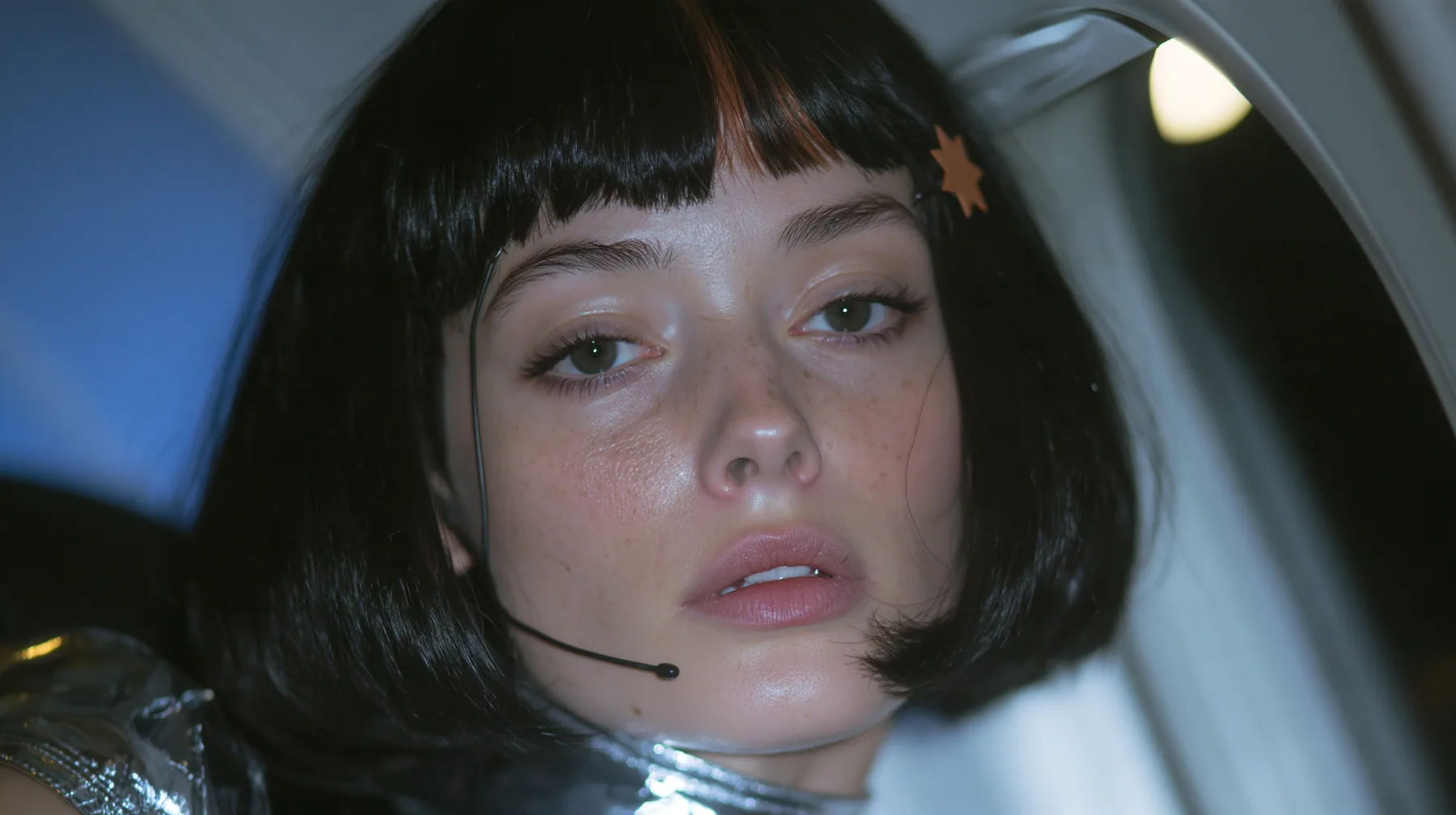 Jet-set high fashion editorial, a couture magazine story shot on a night flight: a close-up of a Caucasian American woman in her late twenties with a grown-up angular face, defined cheekbones and a strong jawline,…