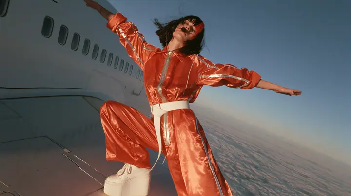 Jet-set high fashion editorial, a couture magazine story shot on a dawn flight: a full-length shot of a Caucasian American woman in her late twenties with pale skin and a glossy black blunt bob with heavy straight…