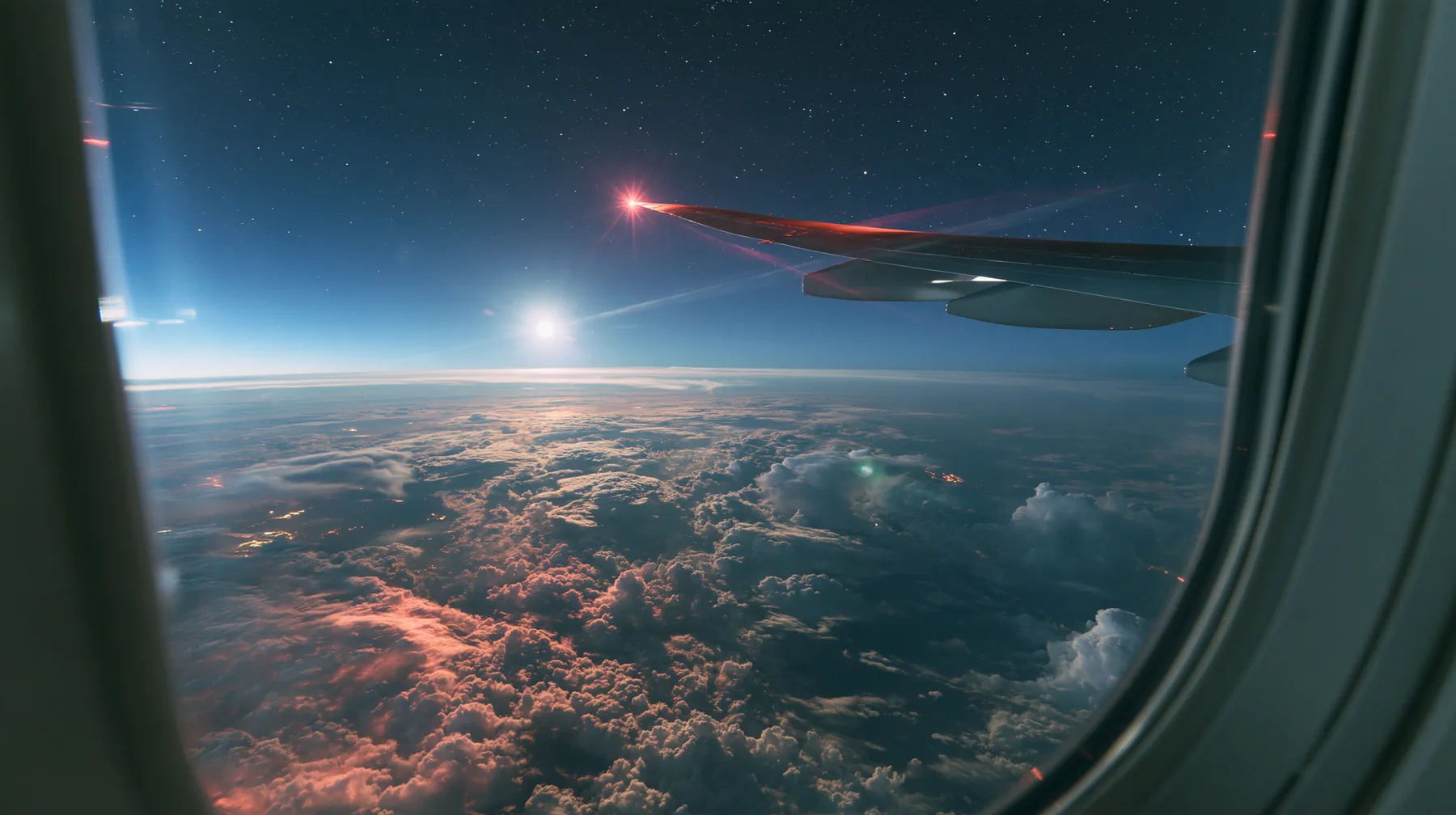 Jet-set editorial: the view out of an oval airliner window at night over a sea of clouds lit by the moon, the wing with its red navigation light, stars, the window frame in the foreground, 35mm lens, no text, no…