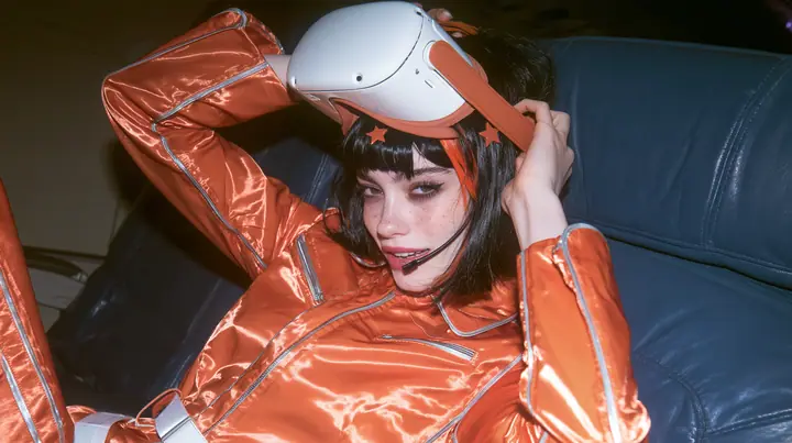 Jet-set fashion editorial, night flight: medium close-up of a Caucasian American woman in her late twenties with a grown-up angular face, pale freckled skin, a glossy black blunt bob with heavy bangs and one…