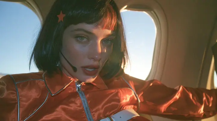 Jet-set fashion editorial, sunrise flight: an eye-level close-up of a Caucasian American woman in her early thirties, a grown woman with elegant mature features, an angular face and defined cheekbones, pale freckled…