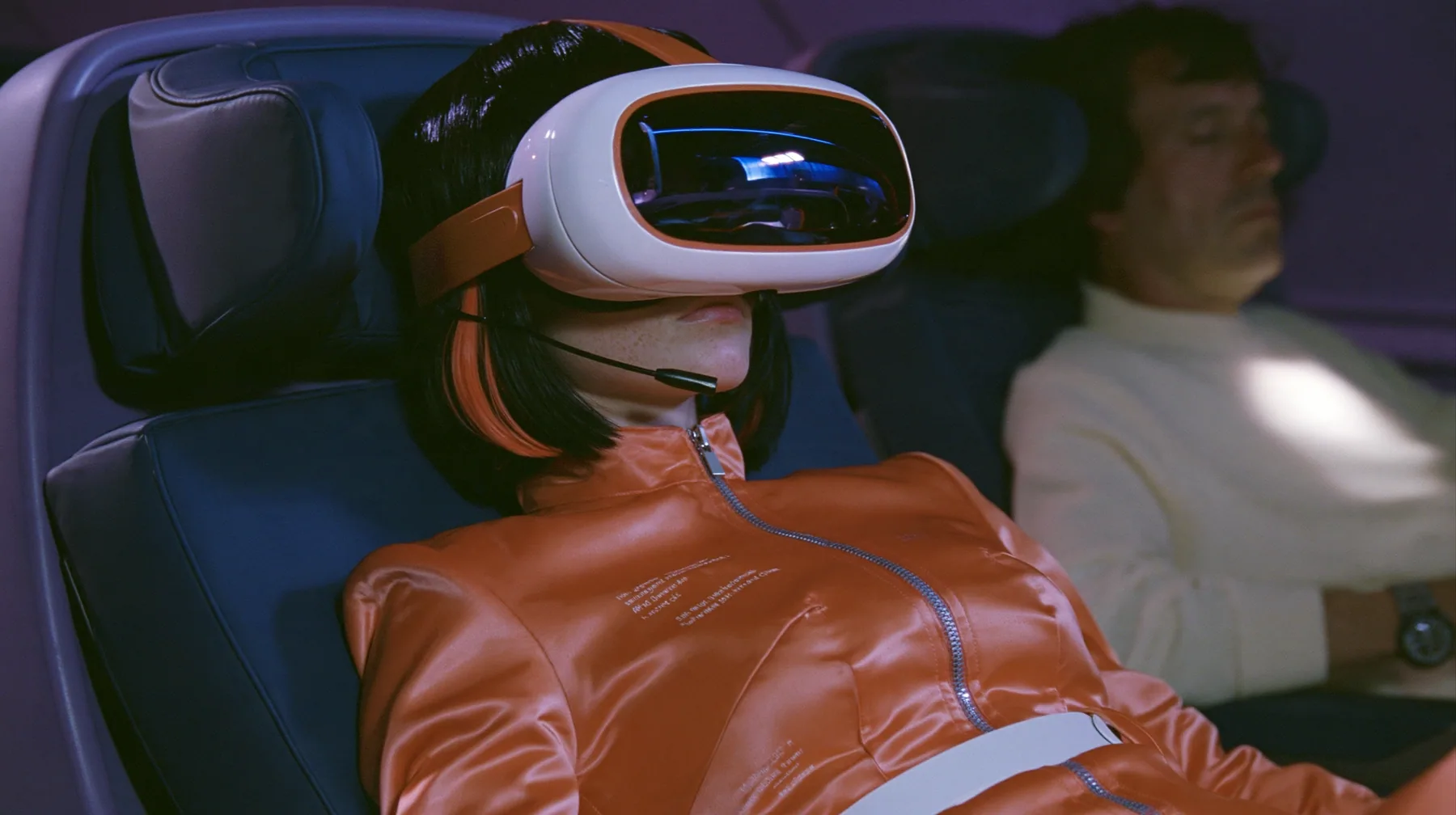 Jet-set fashion editorial, night flight: in the window seat a Caucasian American woman in her early thirties, an angular adult face, pale freckled skin, a glossy black blunt bob with heavy bangs and one clay-orange…