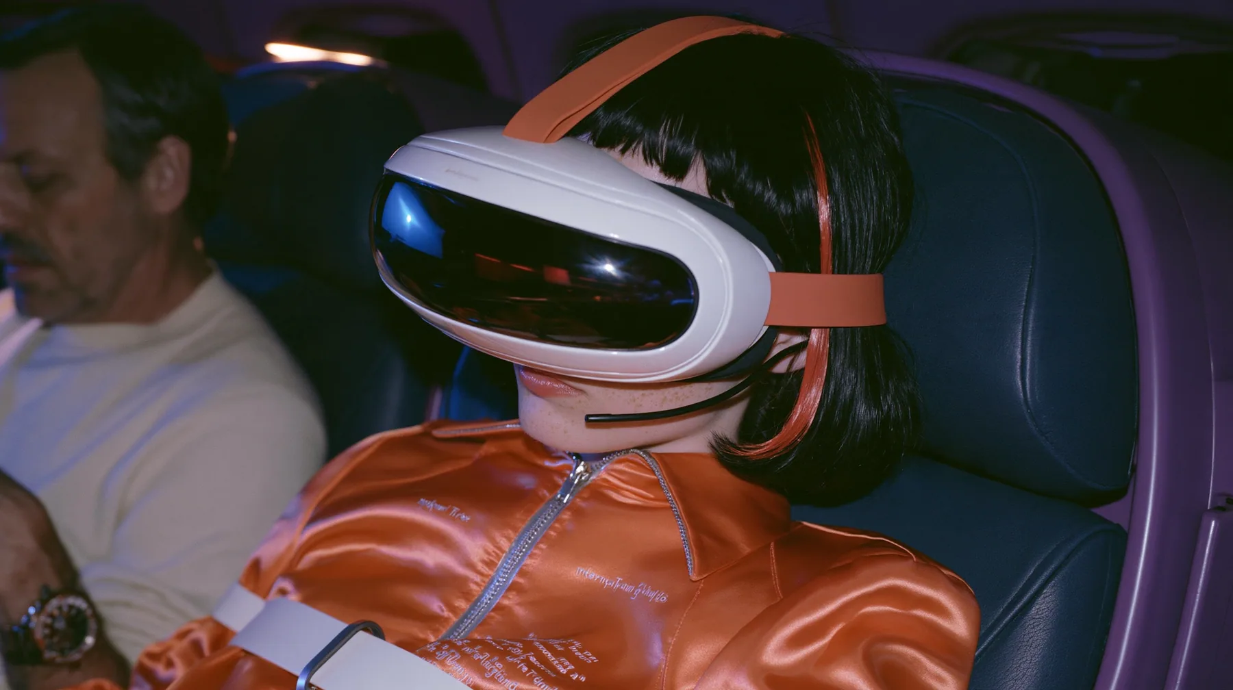 Jet-set fashion editorial, night flight: in the window seat a Caucasian American woman in her early thirties, an angular adult face, pale freckled skin, a glossy black blunt bob with heavy bangs and one clay-orange…