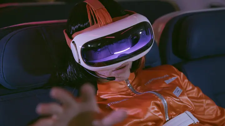 Jet-set fashion editorial, night flight: a Caucasian American woman in her early thirties, an angular adult face, pale freckled skin, a glossy black blunt bob with heavy bangs and one clay-orange streak, a thin black…