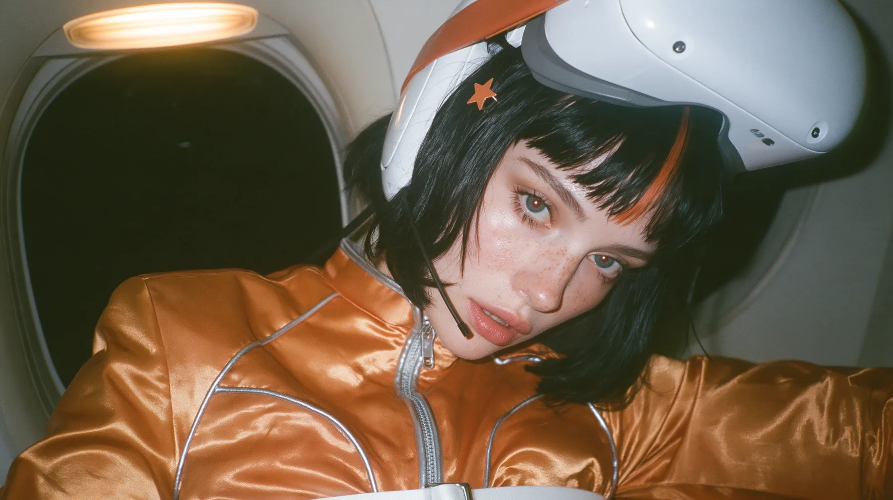 Jet-set fashion editorial, night flight: a close-up portrait of a Caucasian American woman in her early thirties, a grown woman with elegant mature features, an angular face and defined cheekbones, pale freckled…