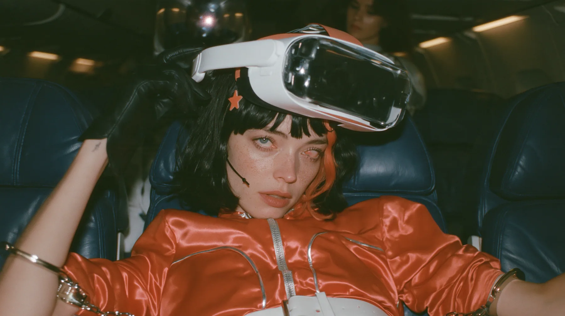 Cinematic close-up film still, night airliner cabin with navy leather seats, all of them empty: a Caucasian woman in her early thirties with an angular adult face, pale freckled skin, a glossy black blunt bob with…