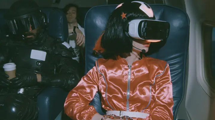 Cinematic film still at 3 AM, dim blue night airliner cabin with navy leather seats, all of them empty: a Caucasian woman in her early thirties with an angular adult face, pale freckled skin, a glossy black blunt bob…