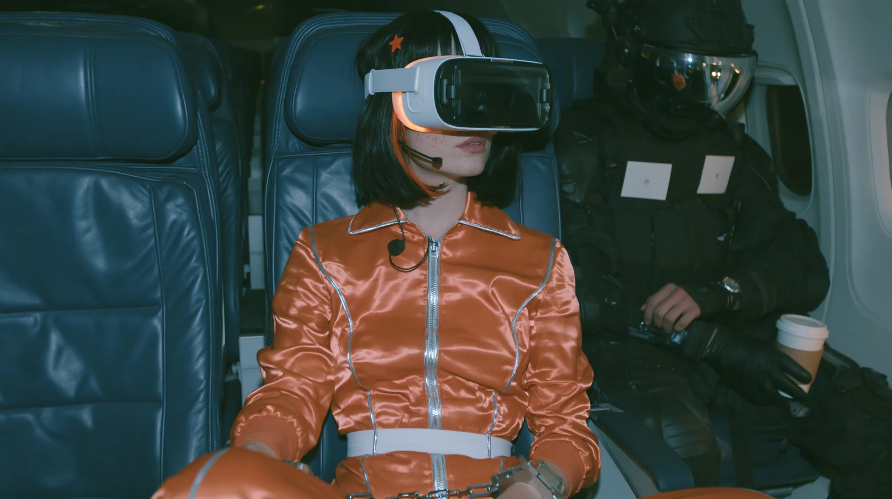Cinematic film still at 3 AM, dim blue night airliner cabin with navy leather seats, all of them empty: a Caucasian woman in her early thirties with an angular adult face, pale freckled skin, a glossy black blunt bob…