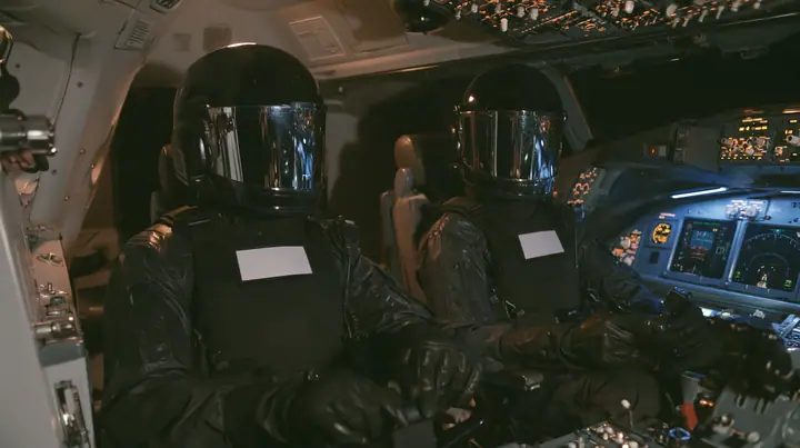 Cinematic film still inside a modern airliner cockpit at night: two guards in matte-black tactical gear and black helmets with mirrored visors hiding their faces, plain white chest patches, black gloves, sit in the…
