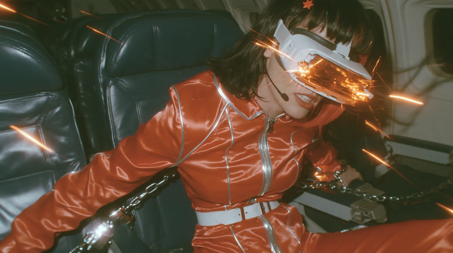 Intense cinematic film still, night airliner cabin with navy leather seats, all of them empty: a Caucasian woman in her early thirties with an angular adult face, pale freckled skin, a glossy black blunt bob with…