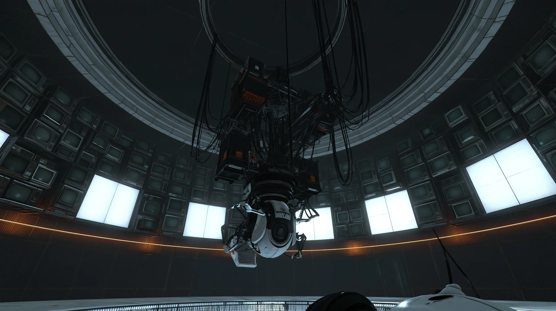 the same dark circular AI chamber with the ceiling ring and hanging cables, its curved walls now lined floor to ceiling with dozens of old CRT monitors and flat panel screens glowing faint white, warm amber accent…