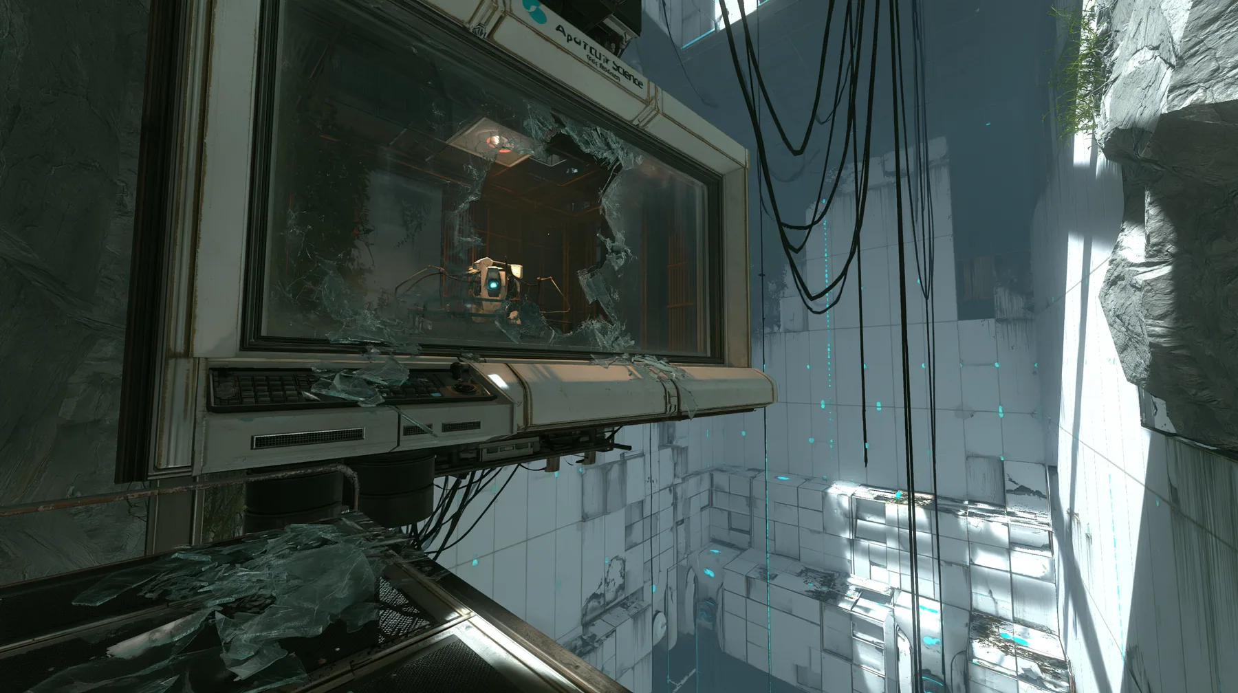 Valve's Portal 2 (2011), a Source engine screenshot: an Aperture Science observation booth high above a test chamber, its big window smashed, glass shards on the console and floor, the decaying white panelled chamber…