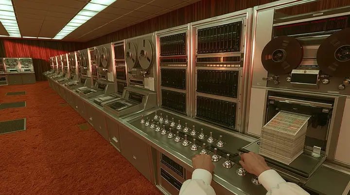 console-height view along a long row of 1960s computers in a wood-panelled room with orange carpet: reel-to-reel tape drives and punch card machines recede diagonally, in the near foreground a scientist's two hands…