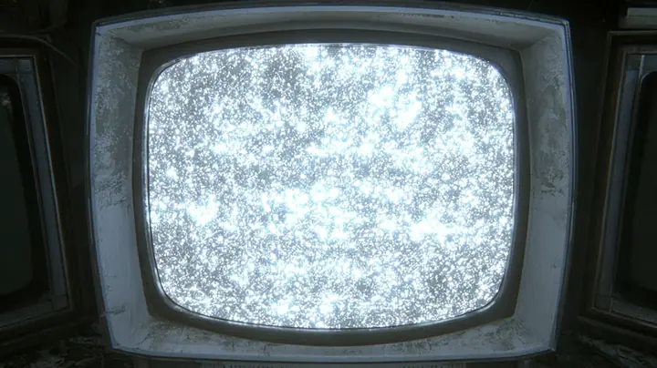 cinematic straight-on close-up of a battered 1970s CRT monitor whose rounded screen fills almost the whole frame, boiling with bright white television static, a scuffed grey-white plastic bezel around it, slivers of…