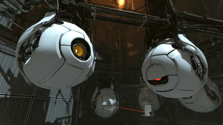Close cinematic film still in a dark Portal 2 chamber: two white personality cores hanging from a steel rail fill the frame, the yellow-eyed one tilted up with its optic wide and bright, hopeful, the red-eyed one…