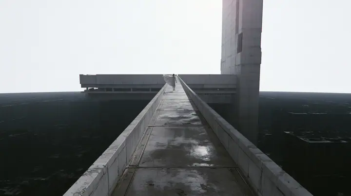 a long concrete catwalk tilting upward and lifting off into a pure white overexposed sky, the dark server hall falling away below, a small figure in a pleated skirt at the far end with the wind in her clothes,…