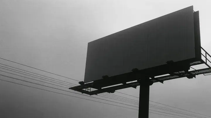 looking up at a huge blank white billboard on a steel pole above the 101 freeway at dawn in thick fog, the billboard face flat and empty, powerlines, grey sky, monochrome, fine grain, no text, no letters, no logos