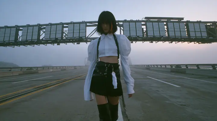 a young woman with a glossy black blunt bob with heavy bangs and one clay-orange streak, a white cropped puff-sleeve shirt, a black pleated skirt with a harness belt and a hanging white garment tag, black knee-high…