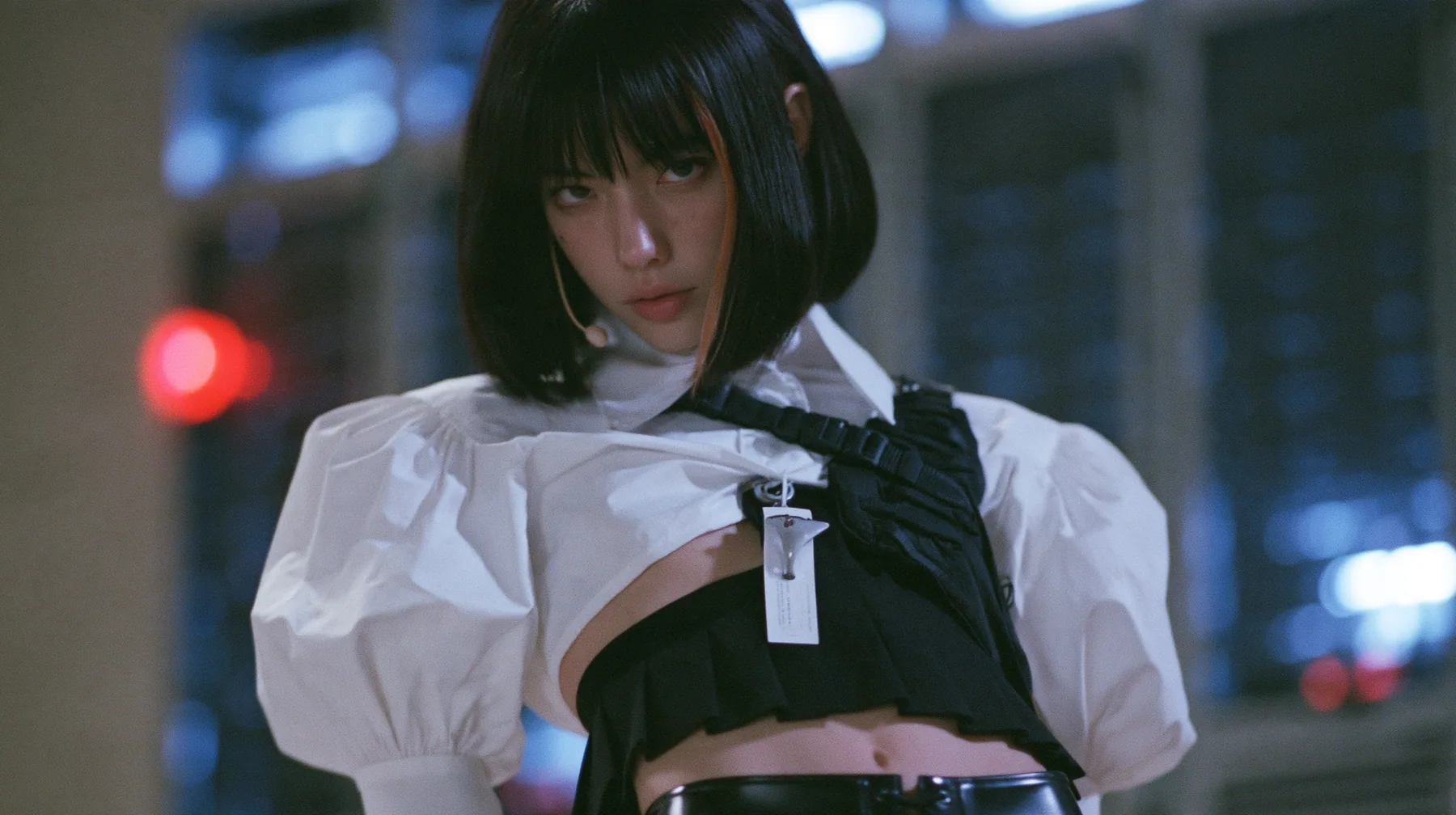 close-up portrait of a young woman with a glossy black blunt bob with heavy bangs and one clay-orange streak, a white cropped puff-sleeve shirt, a black pleated skirt with a harness belt and a hanging white garment…
