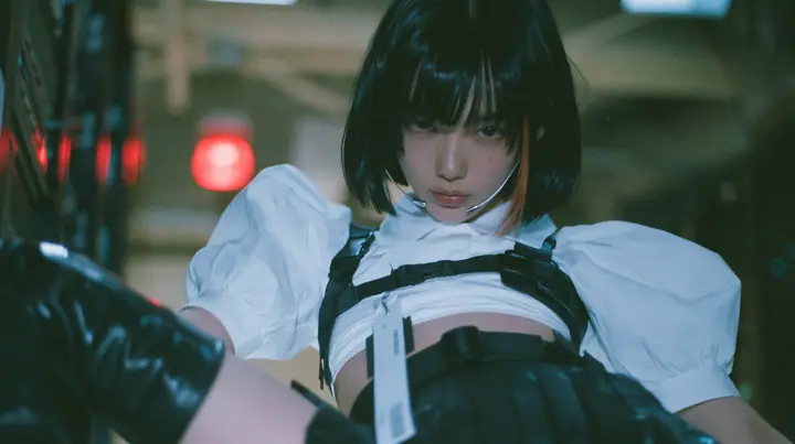 close-up portrait of a young woman with a glossy black blunt bob with heavy bangs and one clay-orange streak, a white cropped puff-sleeve shirt, a black pleated skirt with a harness belt and a hanging white garment…
