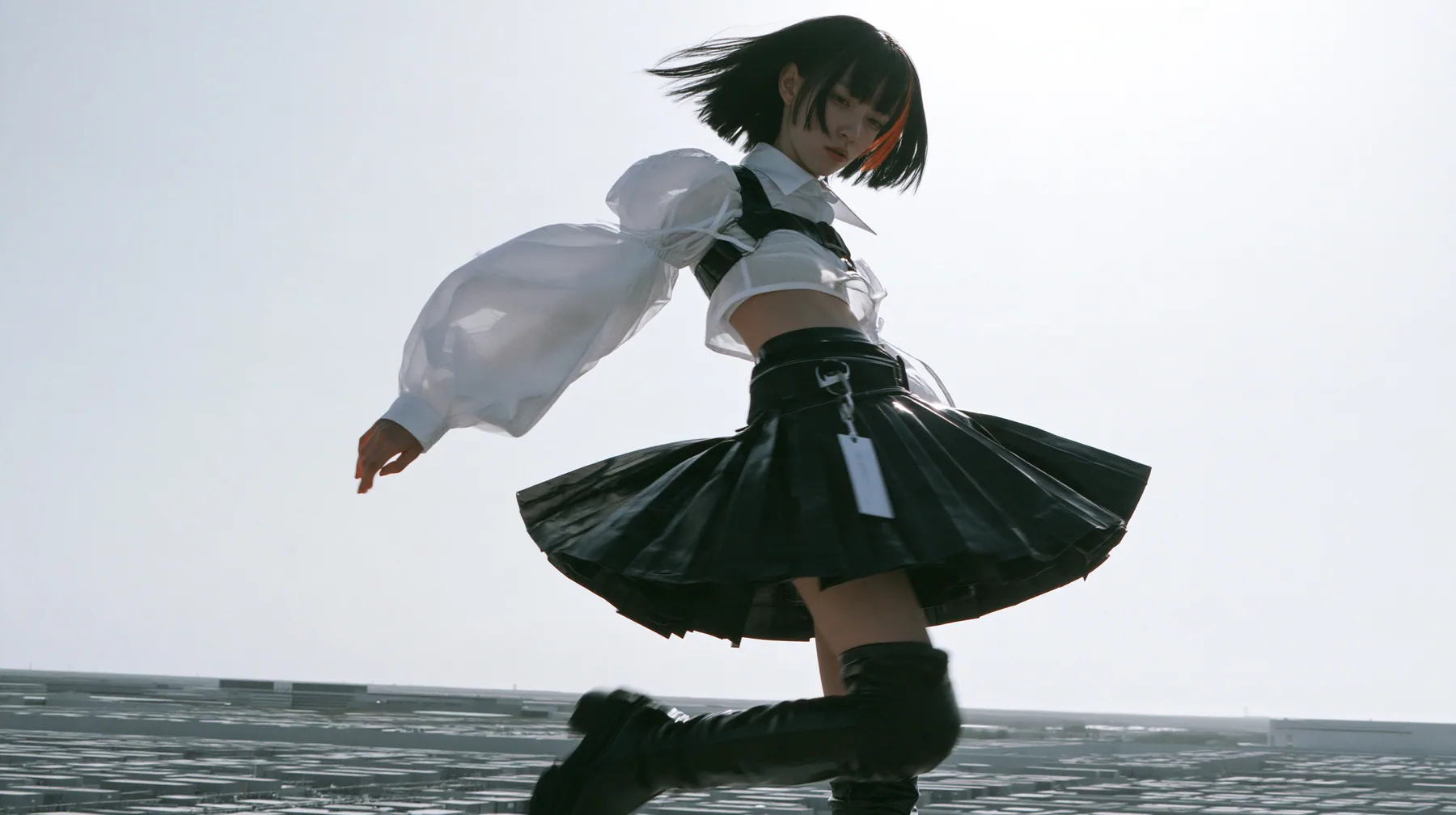 a young woman with a glossy black blunt bob with heavy bangs and one clay-orange streak, a white cropped puff-sleeve shirt, a black pleated skirt with a harness belt and a hanging white garment tag, black knee-high…