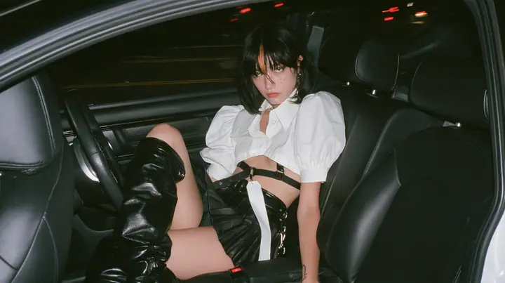 a young woman with a glossy black blunt bob with heavy bangs and one clay-orange streak, a white cropped puff-sleeve shirt, a black pleated skirt with a harness belt and a hanging white garment tag, black knee-high…