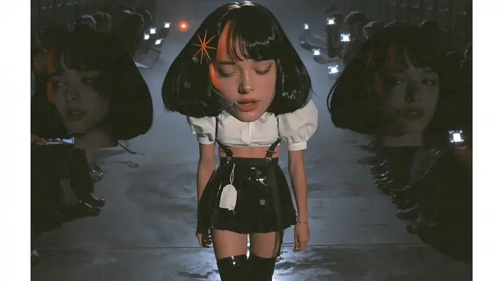 medium shot of a young woman with a glossy black blunt bob with heavy bangs and one clay-orange streak through the bangs, a clay-orange eight-pointed spark hair clip, a thin headset microphone, a white cropped…