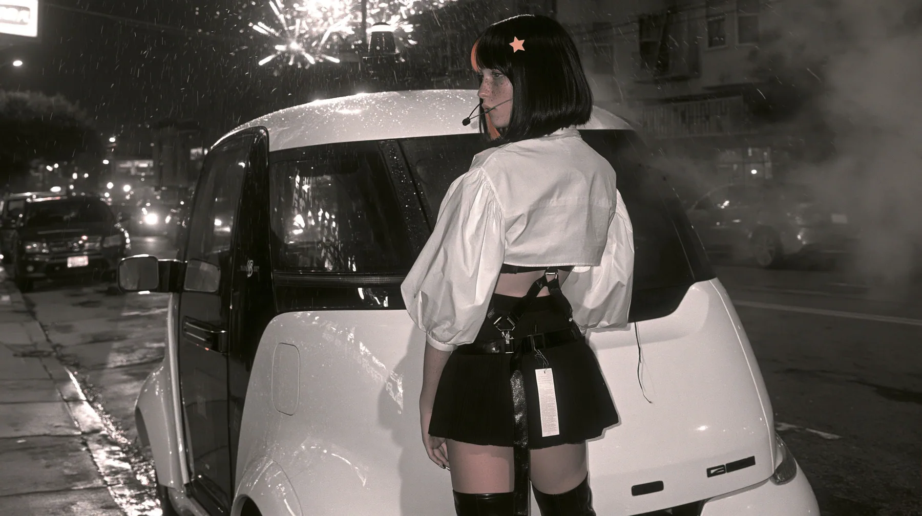 a driverless white robotaxi stopped in a Mission District street at night while fireworks burst low overhead and sparks rain onto its roof, smoke, a young Caucasian American woman with pale skin and light freckles, a…