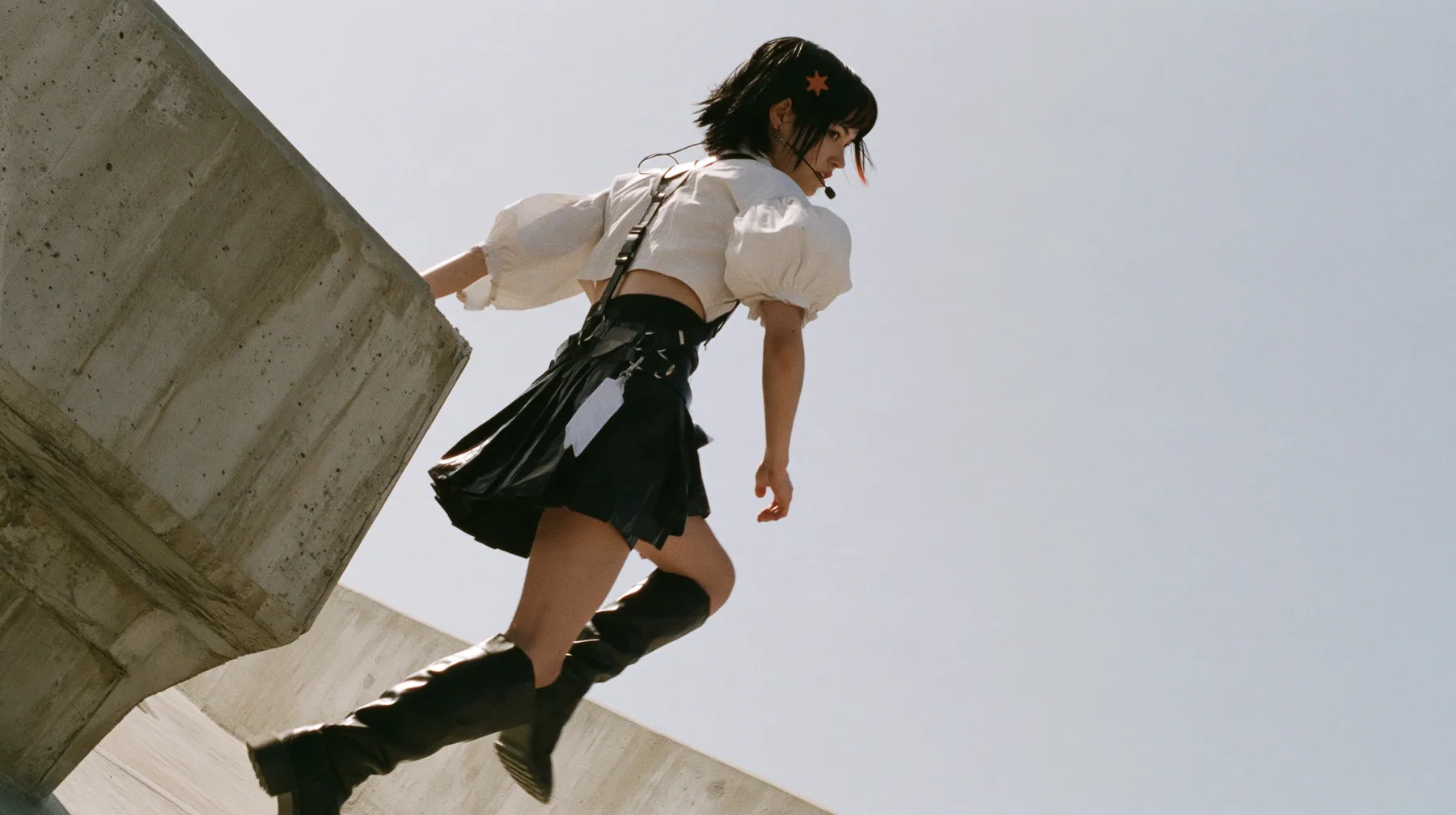 an elevated concrete freeway ramp that ends abruptly in the air against a pure white overexposed sky, a young Caucasian American woman with pale skin and light freckles, a glossy black blunt jaw-length bob with heavy…