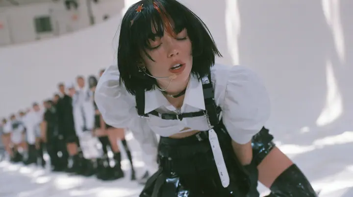 a young Caucasian American woman with pale skin and light freckles, a glossy black blunt jaw-length bob with heavy bangs and one clay-orange streak through the bangs, a small flat clay-orange eight-pointed star hair…