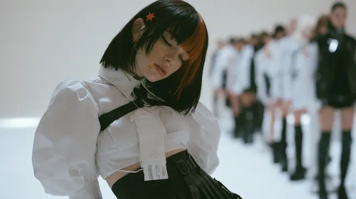 a young Caucasian American woman with pale skin and light freckles, a glossy black blunt jaw-length bob with heavy bangs and one clay-orange streak through the bangs, a small flat clay-orange eight-pointed star hair…