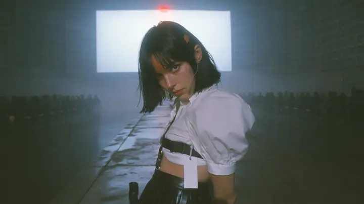 a vast dark data hall in one-point perspective, a narrow wet concrete catwalk running to an enormous blank white billboard panel mounted on the far wall, the panel lit by one red lamp, a young Caucasian American…