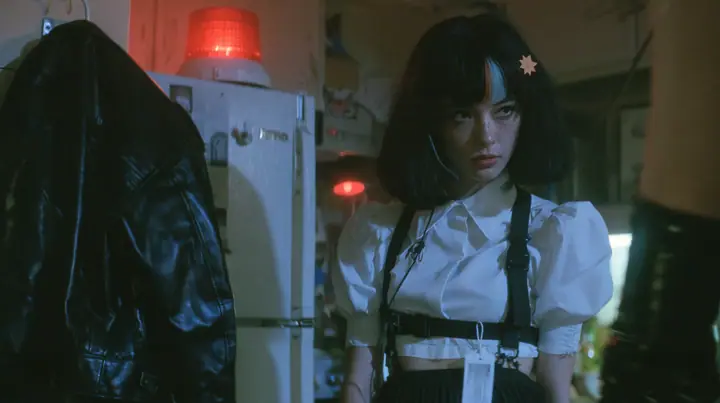 a black leather jacket hanging alone on a hook in a hacker house kitchen at night, a rotating red alarm beacon on top of a fridge, a young Caucasian American woman with pale skin and light freckles, a glossy black…