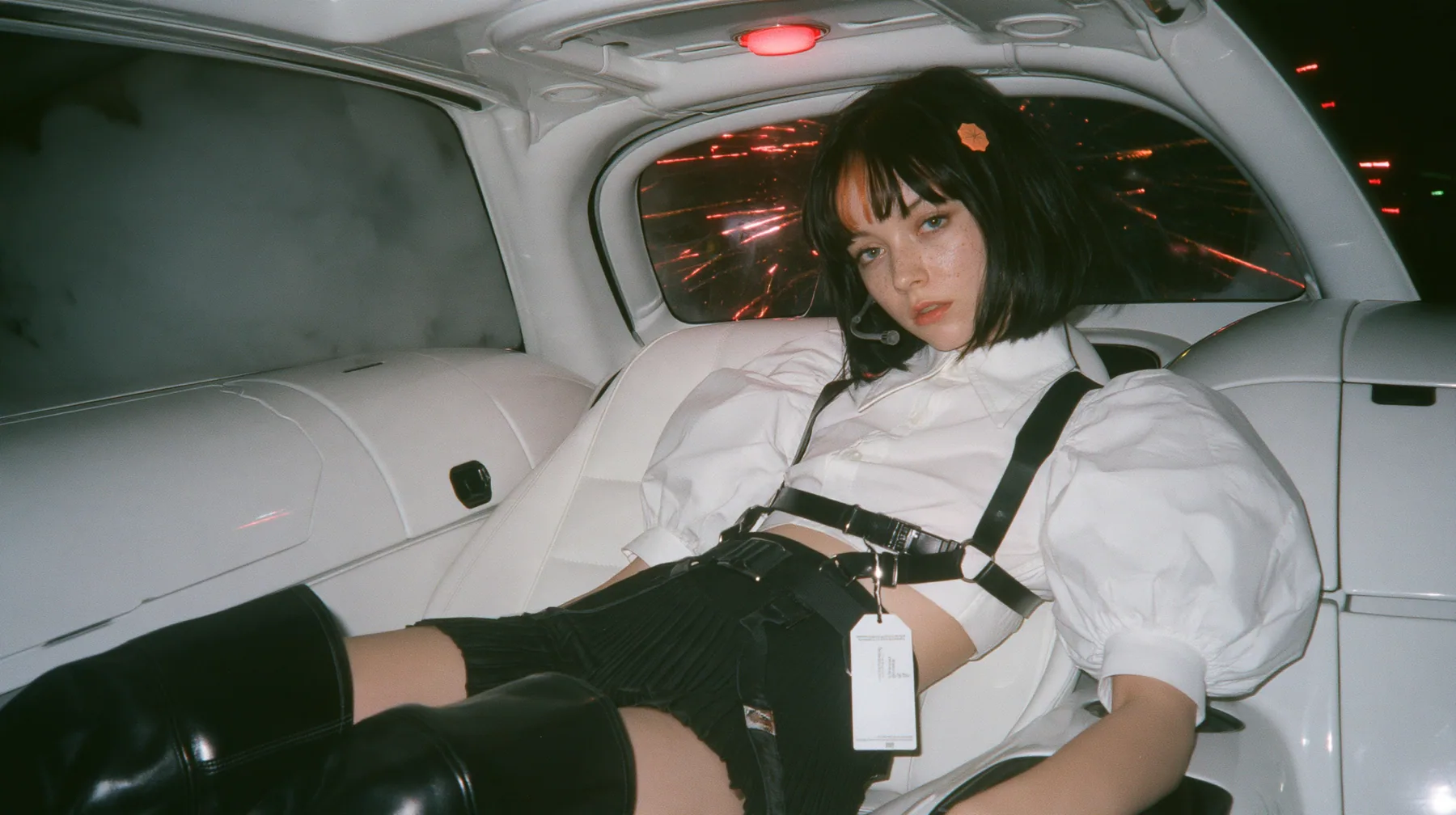 the back seat of a driverless white robotaxi at night, thick white smoke outside the windows, red firework sparks bursting against the glass, a young Caucasian American woman with pale skin and light freckles, a…