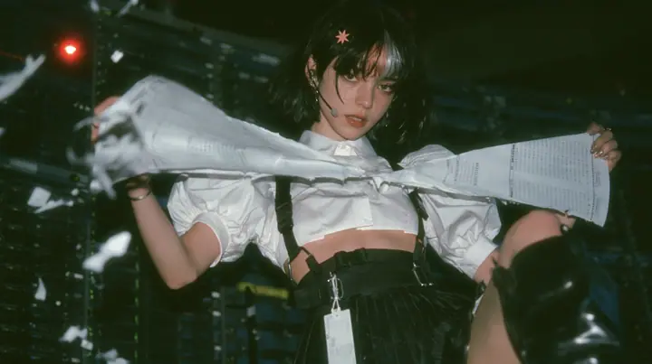a young Caucasian American woman with pale skin and light freckles, a glossy black blunt jaw-length bob with heavy bangs and one clay-orange streak through the bangs, a small flat clay-orange eight-pointed star hair…