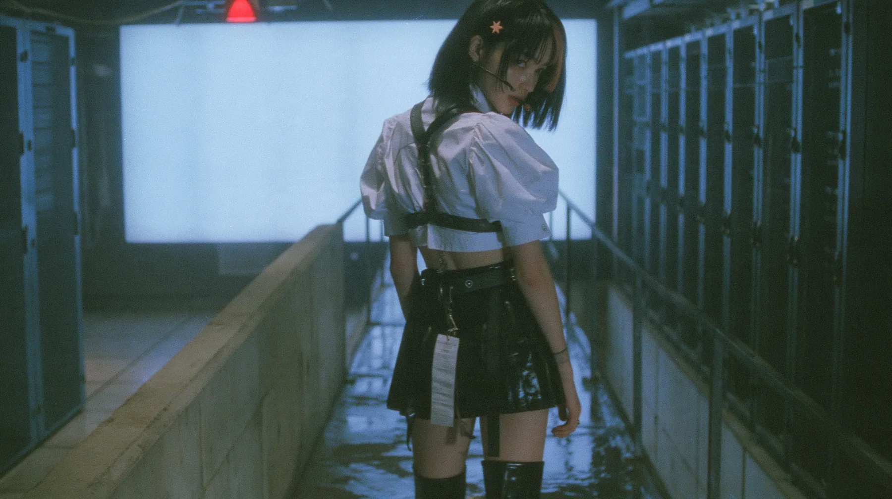 a young Caucasian American woman with pale skin and light freckles, a glossy black blunt jaw-length bob with heavy bangs and one clay-orange streak through the bangs, a small flat clay-orange eight-pointed star hair…