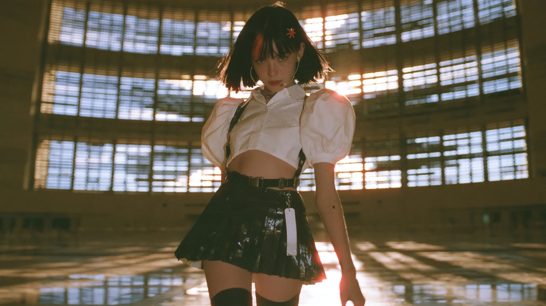 a young Caucasian American woman with pale skin and light freckles, a glossy black blunt jaw-length bob with heavy bangs and one clay-orange streak through the bangs, a small flat clay-orange eight-pointed star hair…
