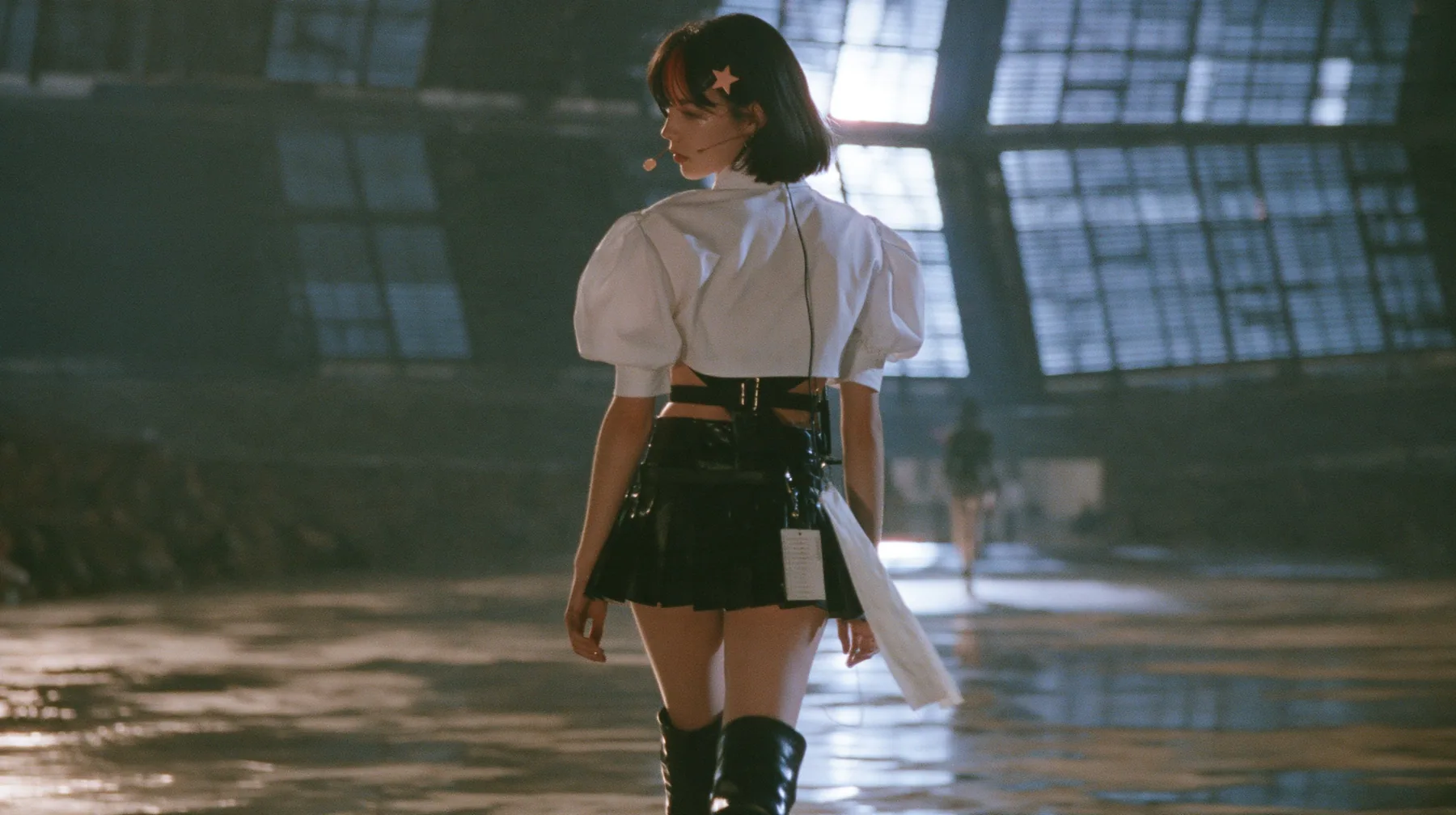 a young Caucasian American woman with pale skin and light freckles, a glossy black blunt jaw-length bob with heavy bangs and one clay-orange streak through the bangs, a small flat clay-orange eight-pointed star hair…
