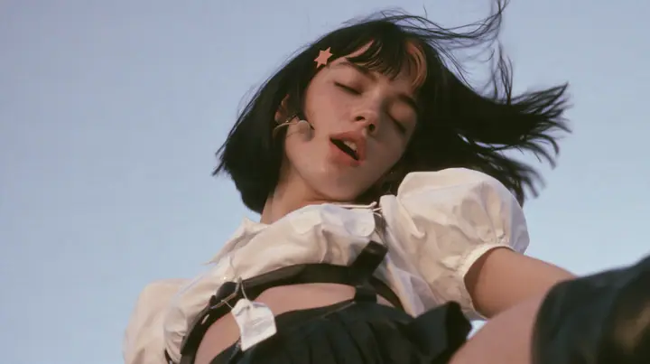 close-up of a young Caucasian American woman with pale skin and light freckles, a glossy black blunt jaw-length bob with heavy bangs and one clay-orange streak through the bangs, a small flat clay-orange…