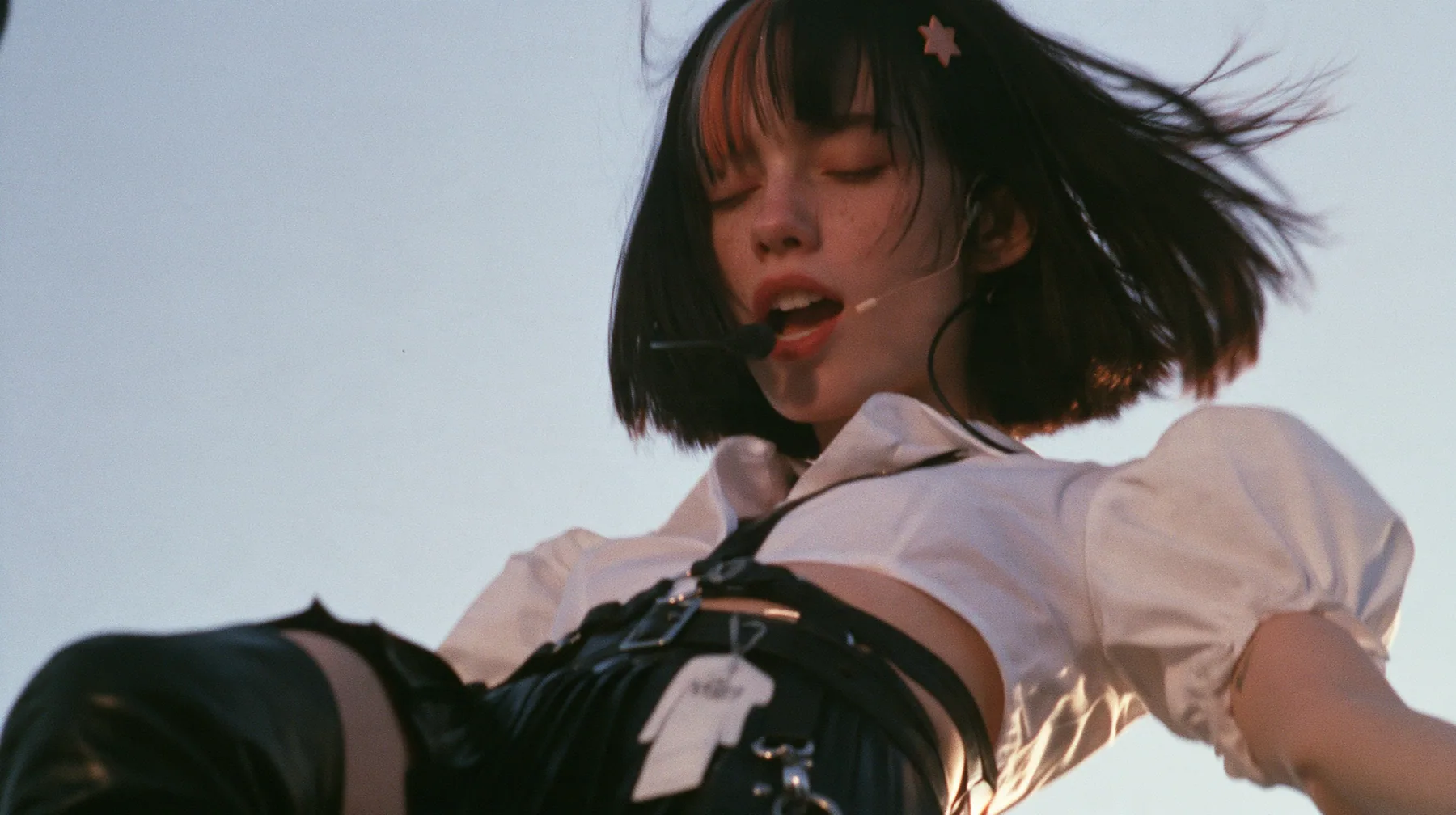 close-up of a young Caucasian American woman with pale skin and light freckles, a glossy black blunt jaw-length bob with heavy bangs and one clay-orange streak through the bangs, a small flat clay-orange…