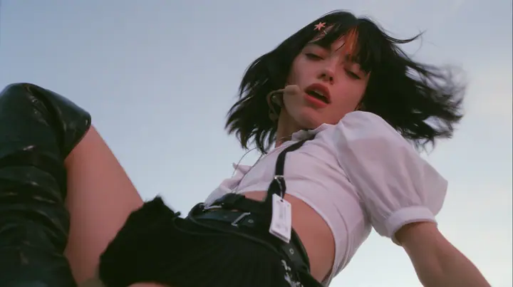 close-up of a young Caucasian American woman with pale skin and light freckles, a glossy black blunt jaw-length bob with heavy bangs and one clay-orange streak through the bangs, a small flat clay-orange…
