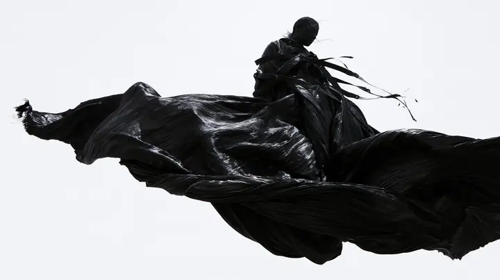 a huge black pleated fabric whipping in wind against a white void, harness straps flying, high-key white void, pure white paper light, hard clean black shadows, monochrome, no text, no letters, no logos