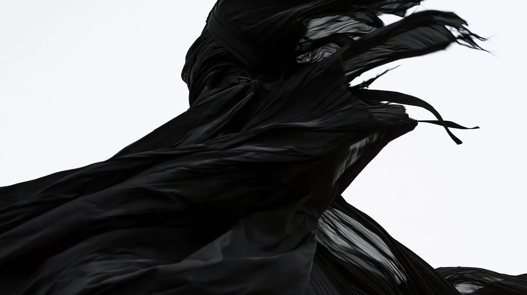 a huge black pleated fabric whipping in wind against a white void, harness straps flying, high-key white void, pure white paper light, hard clean black shadows, monochrome, no text, no letters, no logos