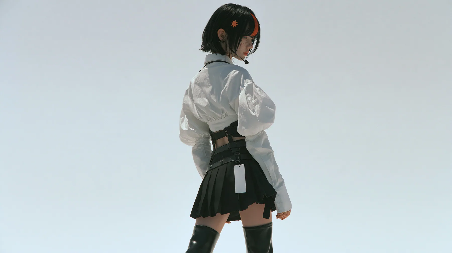 a young Caucasian American woman with pale skin and light freckles, a glossy black blunt jaw-length bob with heavy bangs and one clay-orange streak through the bangs, a small flat clay-orange eight-pointed star hair…