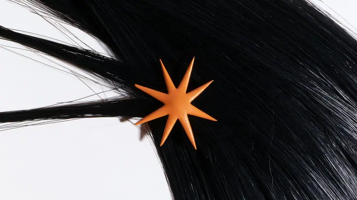 extreme close-up of an eight-pointed clay-orange spark hair clip in black hair against white, high-key white paper, one clay-orange #D97757 accent as the only colour, soft shadowless light, no text, no letters, no logos