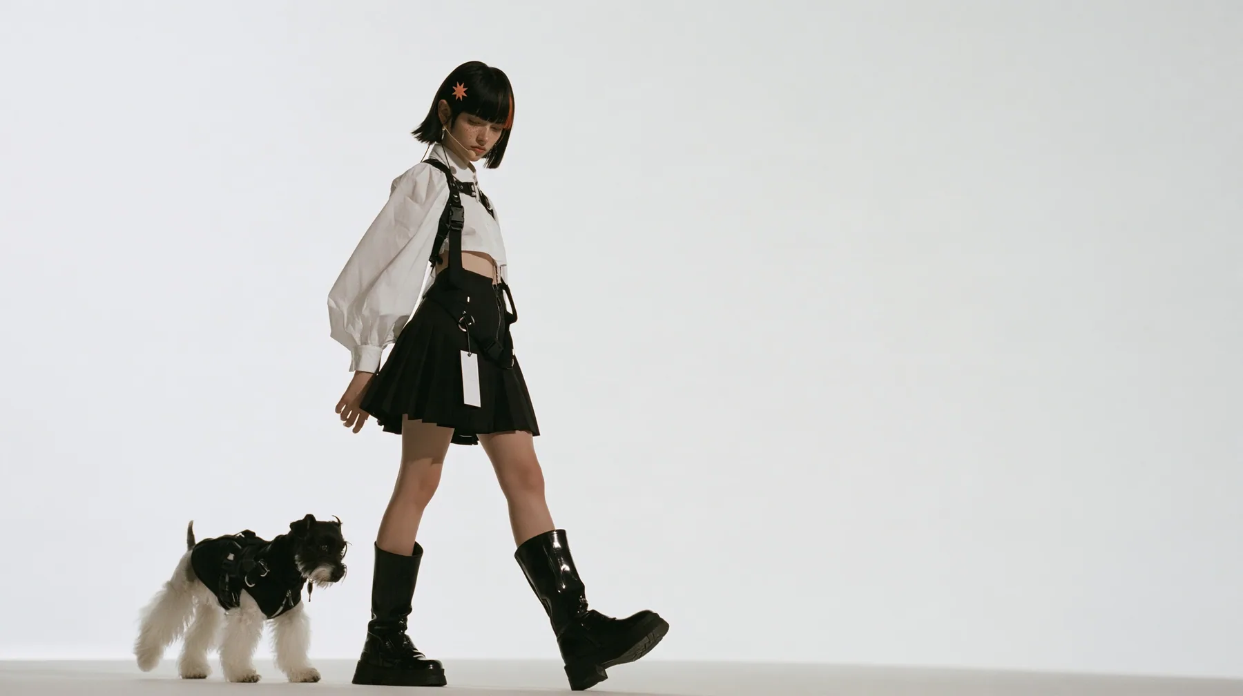 full-length shot of a young Caucasian American woman with pale skin and light freckles, a glossy black blunt jaw-length bob with heavy bangs and one clay-orange streak through the bangs, a small flat clay-orange…