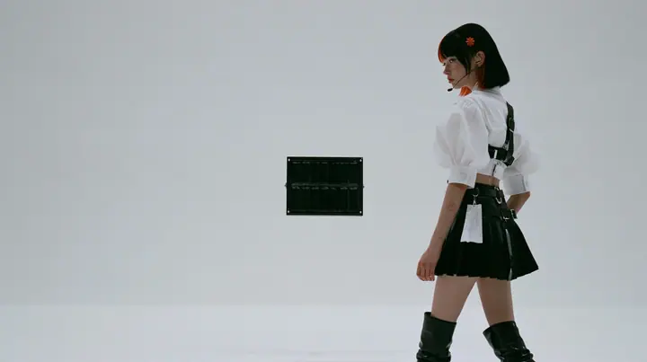 wide shot of a small black split-flap board with blank flaps alone on a seamless white paper wall, a young Caucasian American woman with pale skin and light freckles, a glossy black blunt jaw-length bob with heavy…