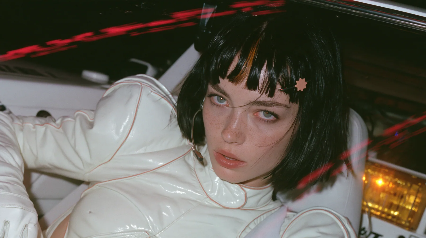 close-up, a 28-year-old Caucasian American woman with a grown-up angular face, defined cheekbones and a strong jawline, pale skin and light freckles, a glossy black blunt jaw-length bob with heavy straight bangs and…