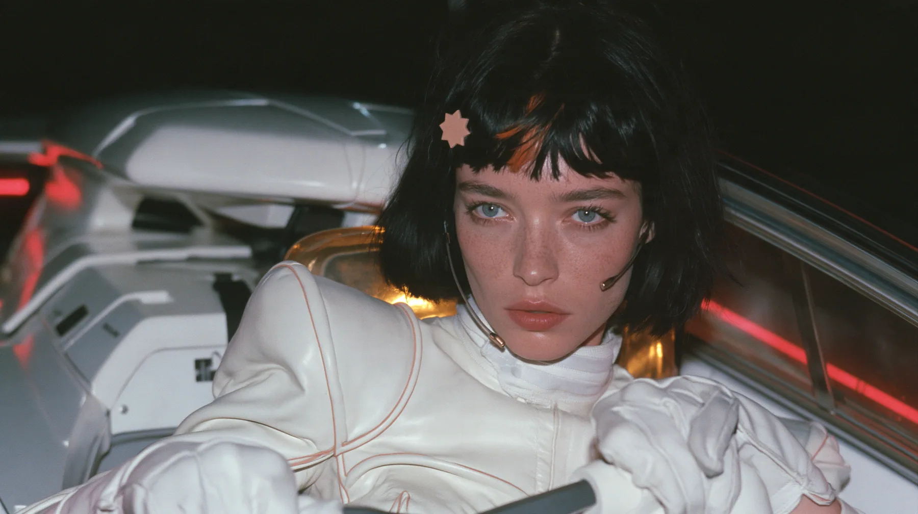 medium close-up, a 28-year-old Caucasian American woman with a grown-up angular face, defined cheekbones and a strong jawline, pale skin and light freckles, a glossy black blunt jaw-length bob with heavy straight…