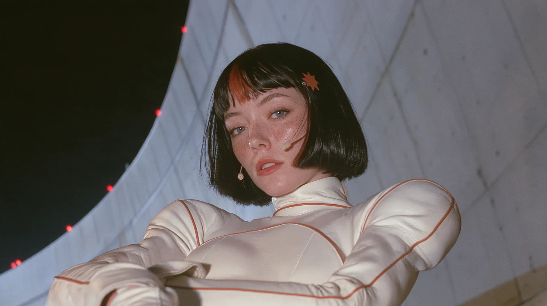 medium shot, a 28-year-old Caucasian American woman with a grown-up angular face, defined cheekbones and a strong jawline, pale skin and light freckles, a glossy black blunt jaw-length bob with heavy straight bangs…